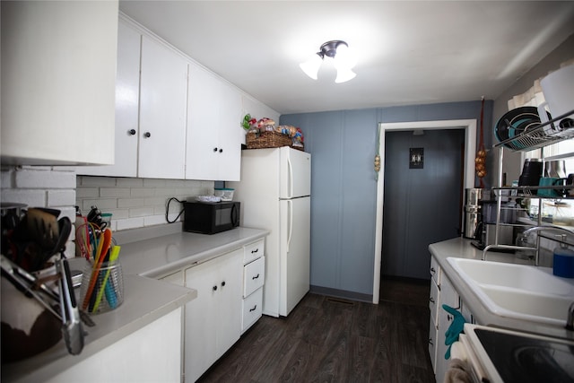 kitchen featuring sink, decorative backsplash, white fridge, dark hardwood / wood-style flooring, and white cabinetry