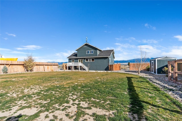 back of house featuring a wooden deck, a yard, and a storage shed