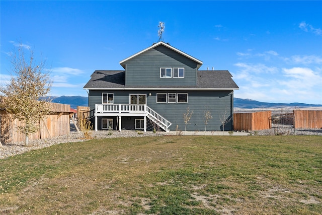 back of property featuring a deck with mountain view and a yard