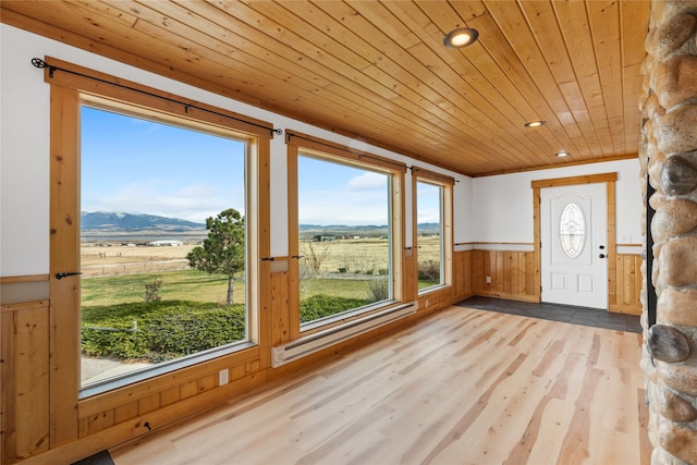 unfurnished sunroom featuring a mountain view, a rural view, and wood ceiling