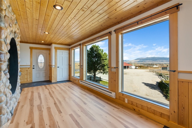 unfurnished sunroom featuring a wealth of natural light, a mountain view, and wooden ceiling