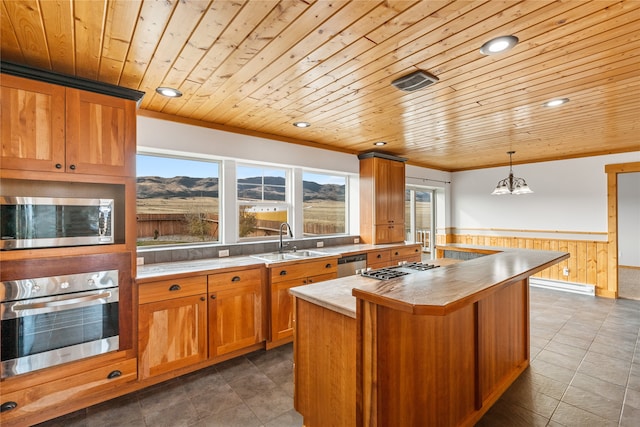 kitchen with sink, an island with sink, pendant lighting, wood ceiling, and appliances with stainless steel finishes