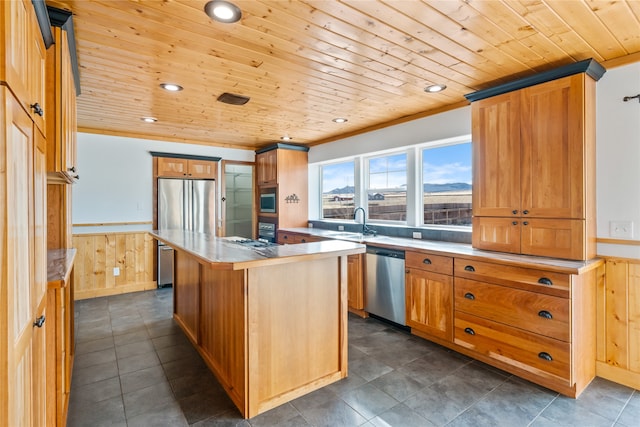 kitchen with a center island, wooden ceiling, stainless steel appliances, crown molding, and wood walls