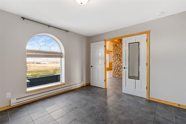 spare room featuring a baseboard radiator and dark tile patterned flooring