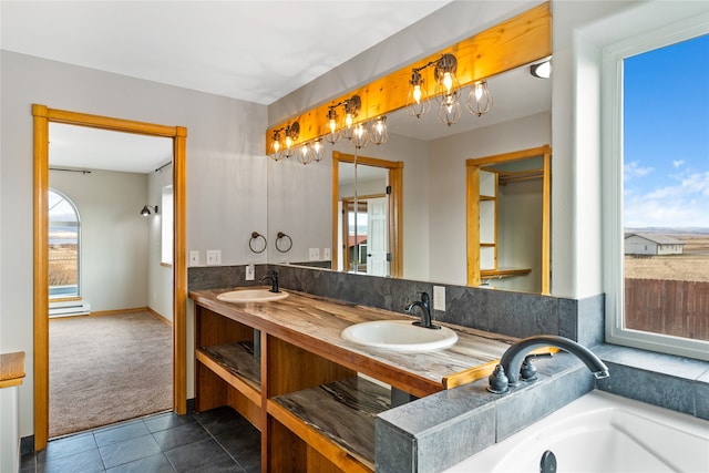 bathroom featuring tile patterned floors, a bathtub, vanity, and an inviting chandelier