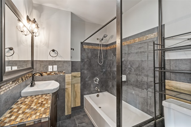 full bathroom with tiled shower / bath combo, tile patterned flooring, toilet, vanity, and tile walls