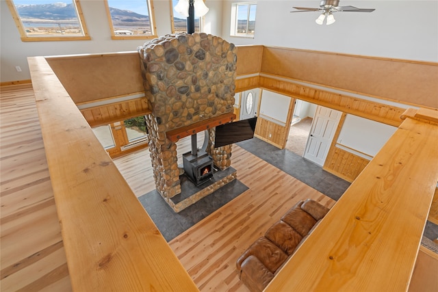 living room featuring wood walls, dark hardwood / wood-style floors, ceiling fan, and a wood stove