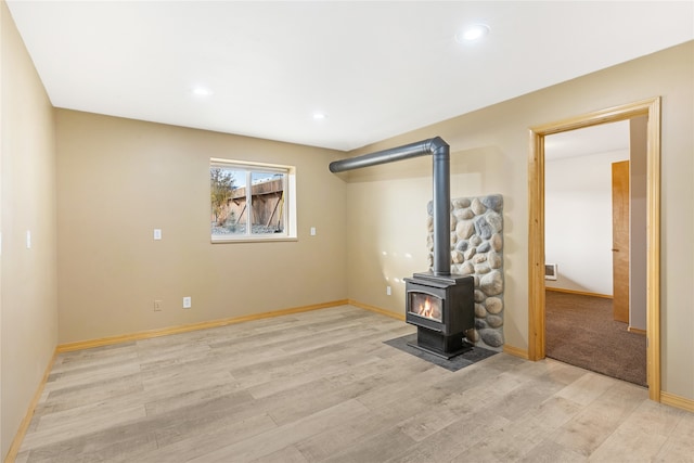 unfurnished living room with a wood stove and light hardwood / wood-style flooring