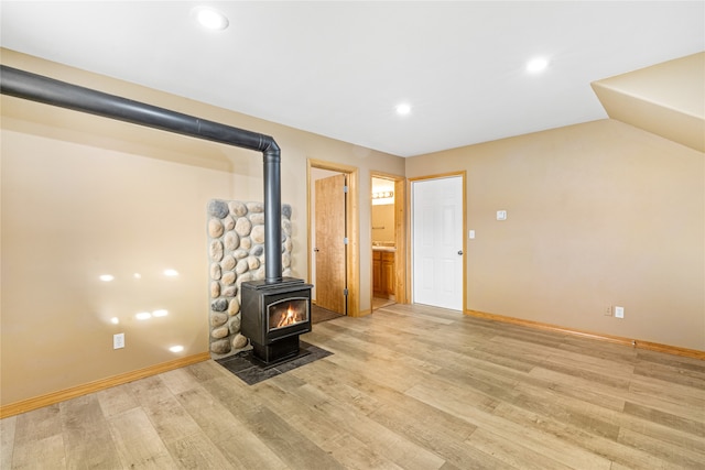 unfurnished living room featuring a wood stove and light wood-type flooring