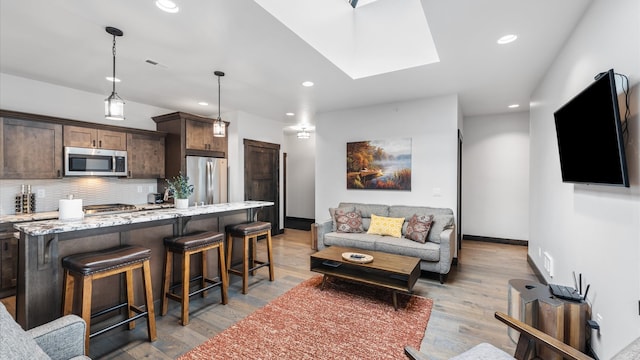 living room with light hardwood / wood-style floors and a skylight