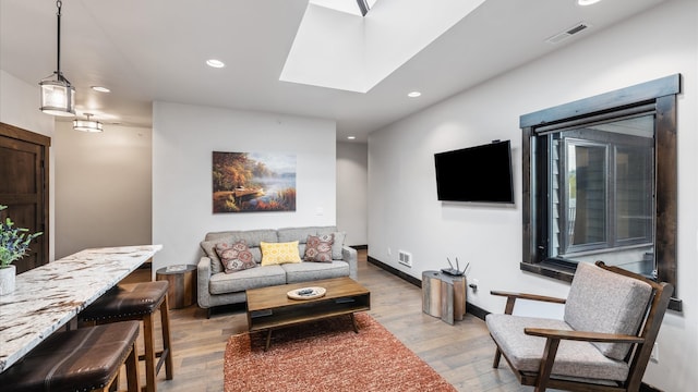 living room with hardwood / wood-style flooring and a skylight