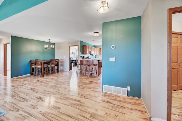 dining area featuring light wood-type flooring and a notable chandelier