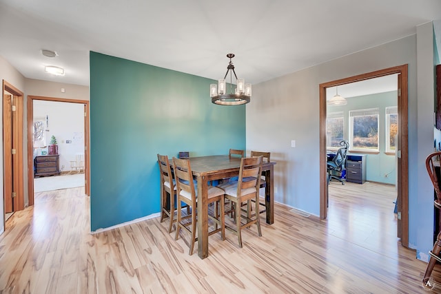 dining space with light wood-type flooring and an inviting chandelier