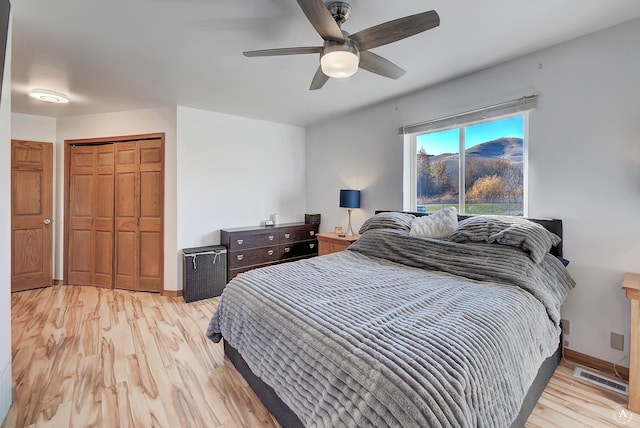 bedroom with a closet, light hardwood / wood-style floors, and ceiling fan