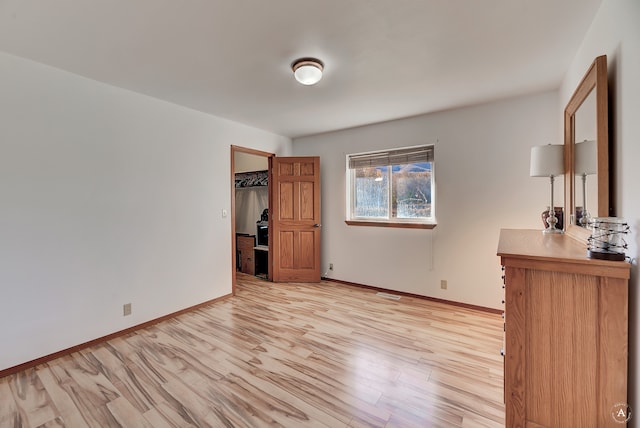 unfurnished bedroom featuring a walk in closet, light wood-type flooring, and a closet