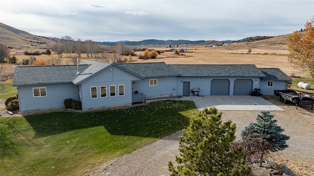 single story home featuring a mountain view, a garage, and a front lawn