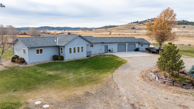 ranch-style house with a mountain view, a garage, and a front lawn