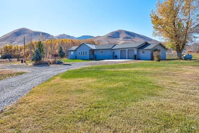 ranch-style house with a mountain view, a front lawn, and a garage