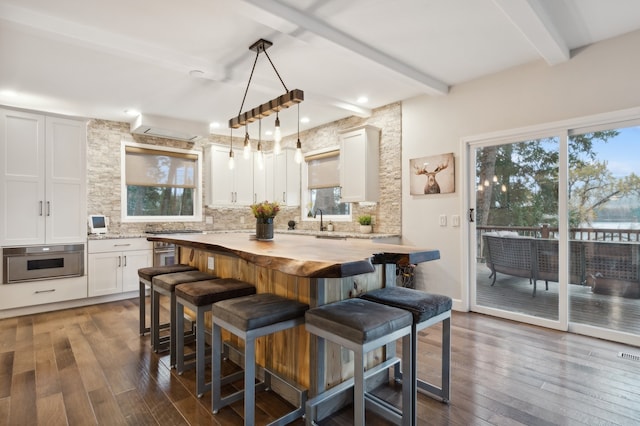 kitchen featuring dark hardwood / wood-style floors, beam ceiling, white cabinetry, and wooden counters