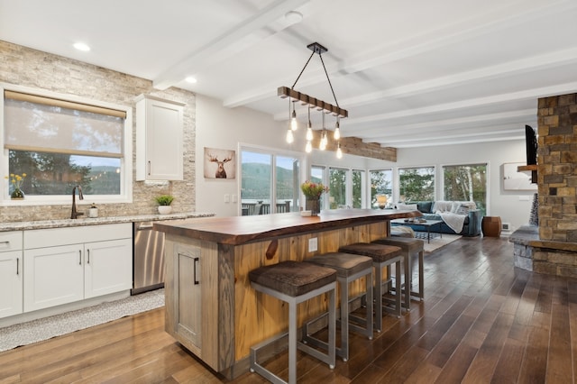 kitchen with a kitchen breakfast bar, dark hardwood / wood-style flooring, white cabinets, and a healthy amount of sunlight