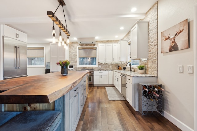 kitchen featuring premium appliances, dark wood-type flooring, sink, butcher block countertops, and white cabinetry