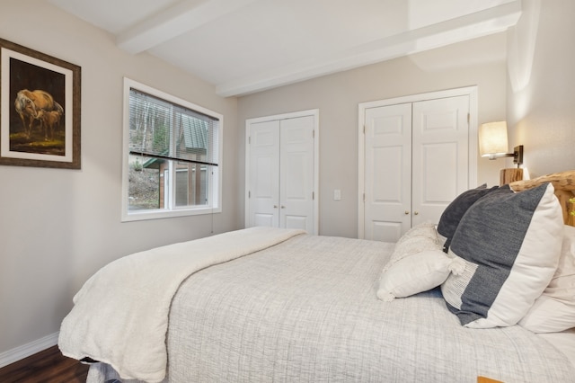 bedroom featuring beamed ceiling, hardwood / wood-style floors, and two closets