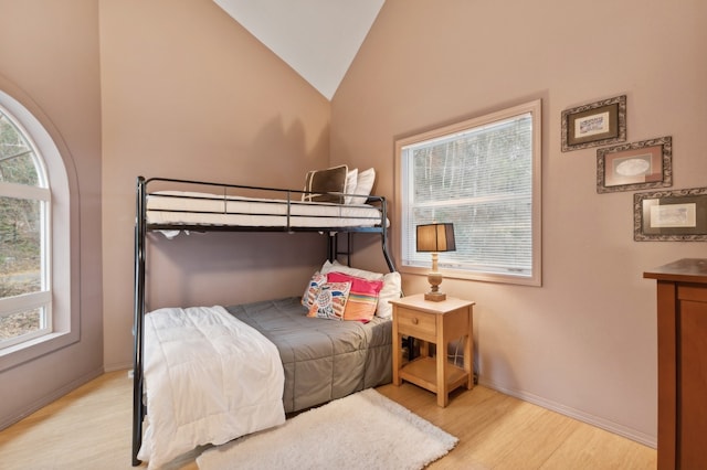 bedroom featuring light wood-type flooring, high vaulted ceiling, and multiple windows