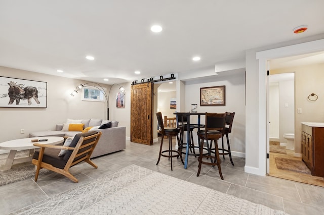 living room with a barn door and light tile patterned flooring