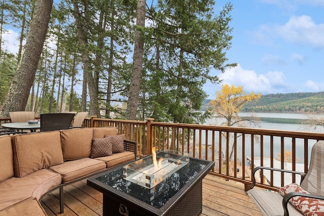 wooden deck with a water view and an outdoor living space with a fire pit