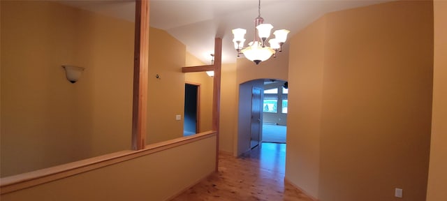 hall featuring lofted ceiling and a notable chandelier