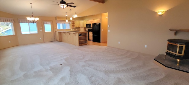 kitchen with a wood stove, vaulted ceiling with beams, kitchen peninsula, light colored carpet, and black appliances