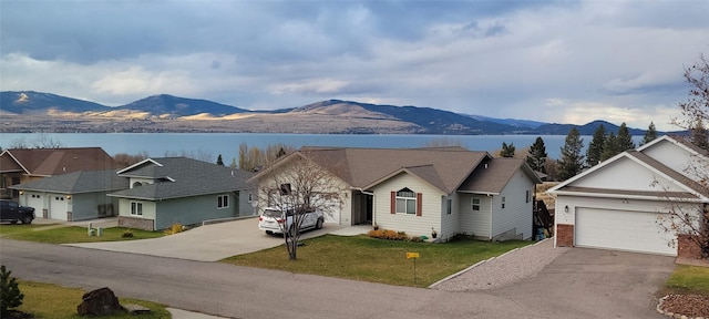 view of front facade featuring aphalt driveway, an attached garage, a front yard, a residential view, and a mountain view