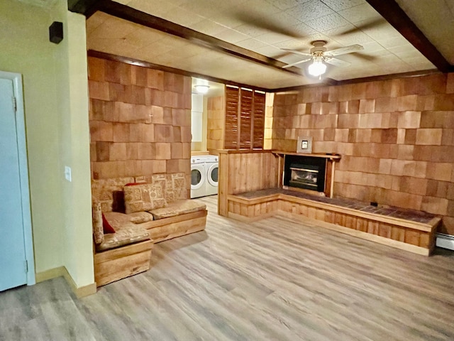 living room featuring hardwood / wood-style flooring, ceiling fan, washer and dryer, a fireplace, and beam ceiling