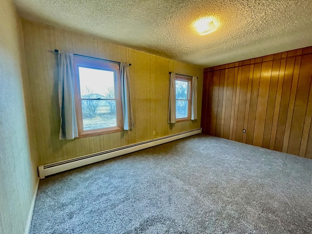 empty room with plenty of natural light, carpet floors, a textured ceiling, and a baseboard heating unit
