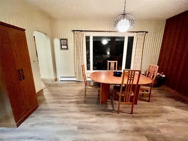 dining space with a textured ceiling, hardwood / wood-style flooring, and a baseboard radiator