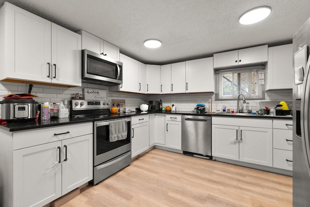 121 Mill Ave, Whitefish, MT 59937 - kitchen featuring stainless steel appliances, a textured ceiling, decorative backsplash, and white cabinets