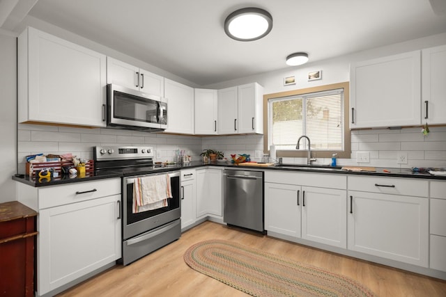 121 Mill Ave, Whitefish, MT 59937 - kitchen featuring stainless steel appliances, dark countertops, light wood-style floors, tasteful backsplash, and white cabinets
