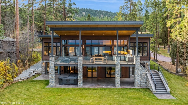 rear view of house featuring a lawn, a patio area, and a jacuzzi