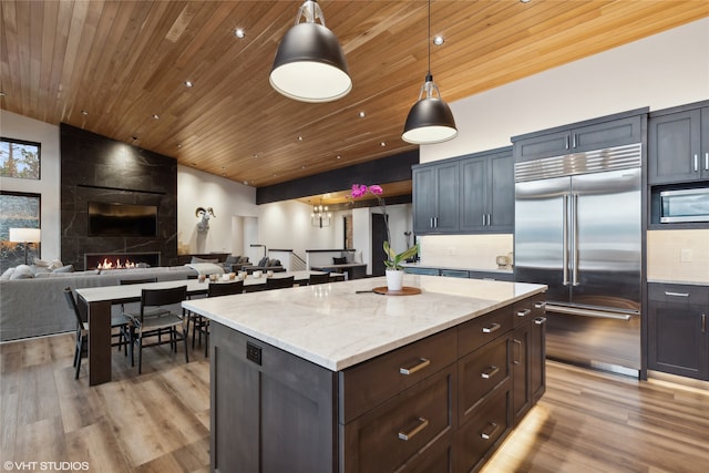 kitchen featuring appliances with stainless steel finishes, wood ceiling, pendant lighting, a fireplace, and light hardwood / wood-style floors