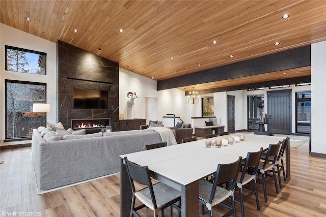 dining space featuring a notable chandelier, wood ceiling, a fireplace, and light hardwood / wood-style flooring