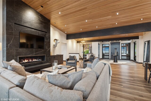 living room featuring a fireplace, light hardwood / wood-style floors, a chandelier, and wood ceiling