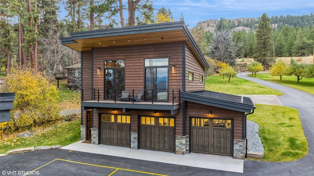 22934 Damaskes Way, Rollins, MT 59931 - modern home with stone siding, an attached garage, a balcony, a mountain view, and a front lawn