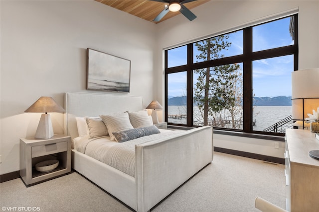 carpeted bedroom with ceiling fan, wood ceiling, a high ceiling, and a water and mountain view