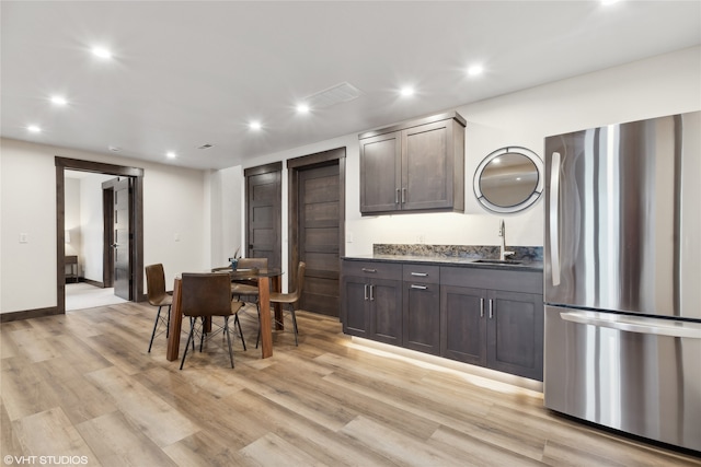 kitchen with dark brown cabinets, stainless steel fridge, light hardwood / wood-style floors, and sink