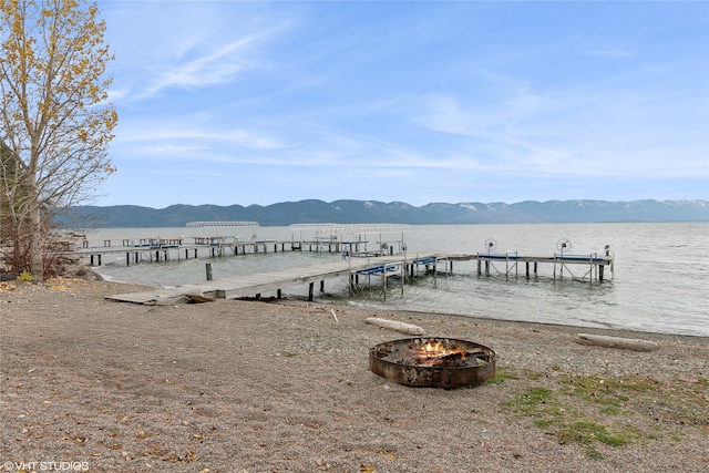 view of dock featuring an outdoor fire pit and a water and mountain view