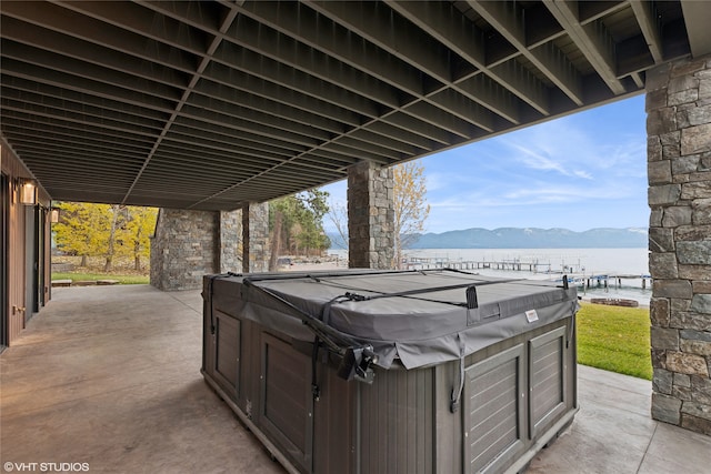 view of patio / terrace featuring a hot tub and a water and mountain view