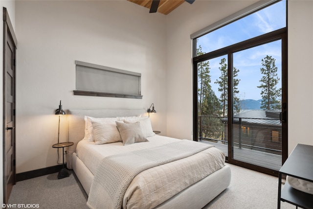 carpeted bedroom with access to exterior, ceiling fan, a mountain view, and a high ceiling