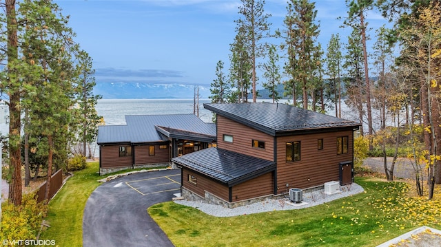 view of front of property with a front yard, central air condition unit, and a water and mountain view