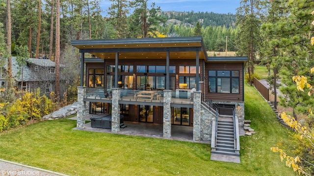 rear view of property featuring a yard, a hot tub, and a patio area