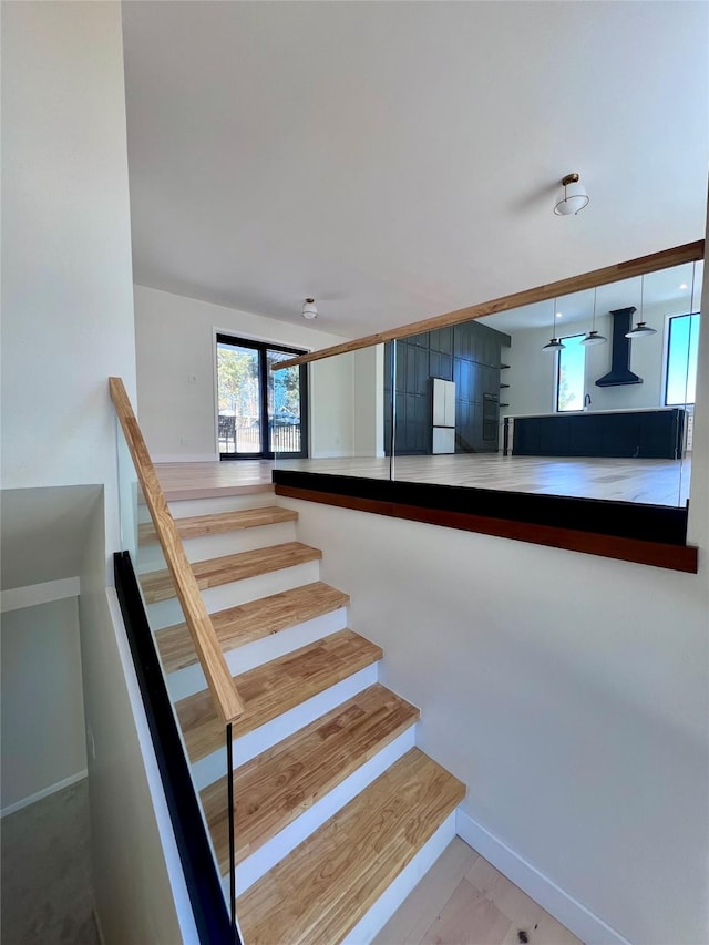 stairway with a healthy amount of sunlight and baseboards